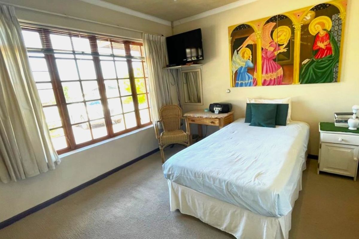 A bedroom featuring large multi-pane windows, neutral carpeting, and standard interior finishes.
