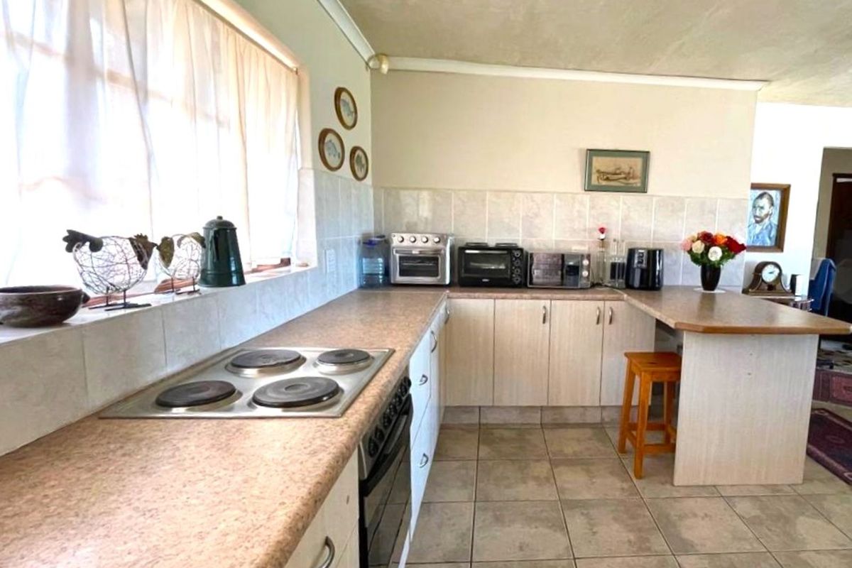 Functional kitchen featuring a built-in electric hob, oven, tiled backsplash, and laminate countertops with ample storage cabinetry.