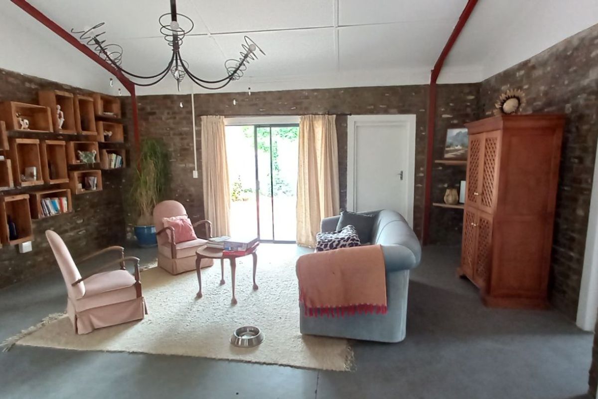 Spacious living room featuring exposed brick walls, concrete flooring, and sliding glass doors providing access to the outdoor area.