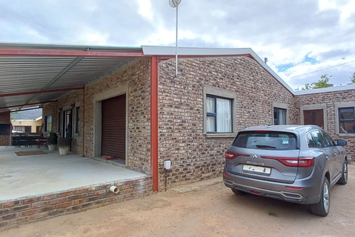 Exterior view of the property featuring a face-brick facade, a covered patio area with a metal roof, and an adjacent driveway space.