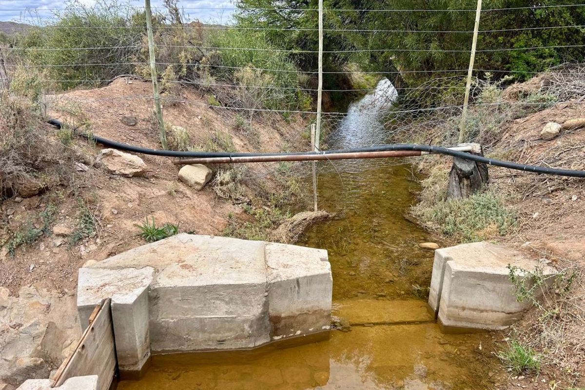 An outdoor irrigation channel featuring a concrete sluice gate and water management infrastructure on the farm property.