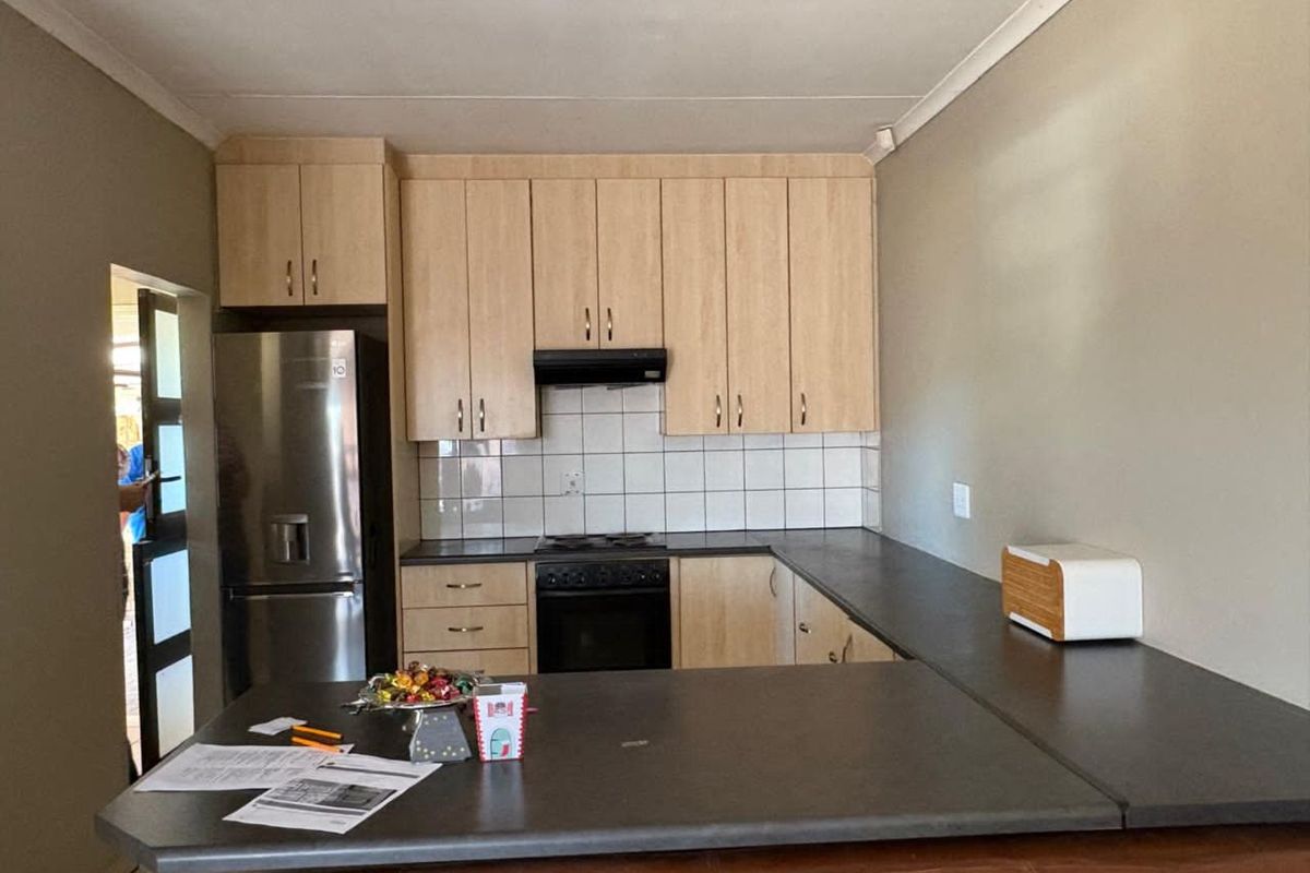 Functional kitchen featuring light wood cabinetry, dark countertops, tiled backsplash, and a built-in oven with extractor fan.
