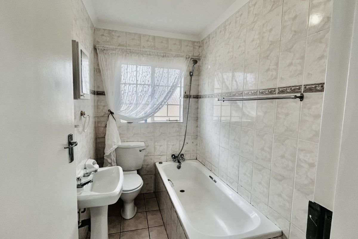 A functional bathroom featuring a pedestal basin, toilet, and a combined bathtub with a shower mixer.