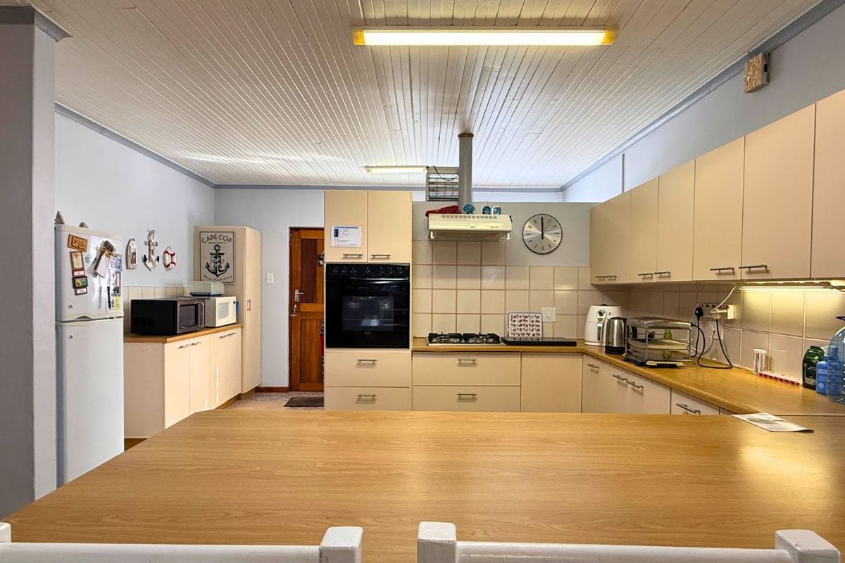 A functional kitchen featuring light-toned cabinetry, built-in oven, gas hob, extractor fan, and tiled splashbacks, offering a practical layout for daily meal preparation.