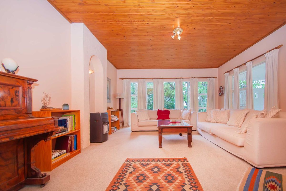 A spacious living room featuring a distinctive timber-paneled ceiling, large windows allowing natural light, and a built-in fireplace alcove.