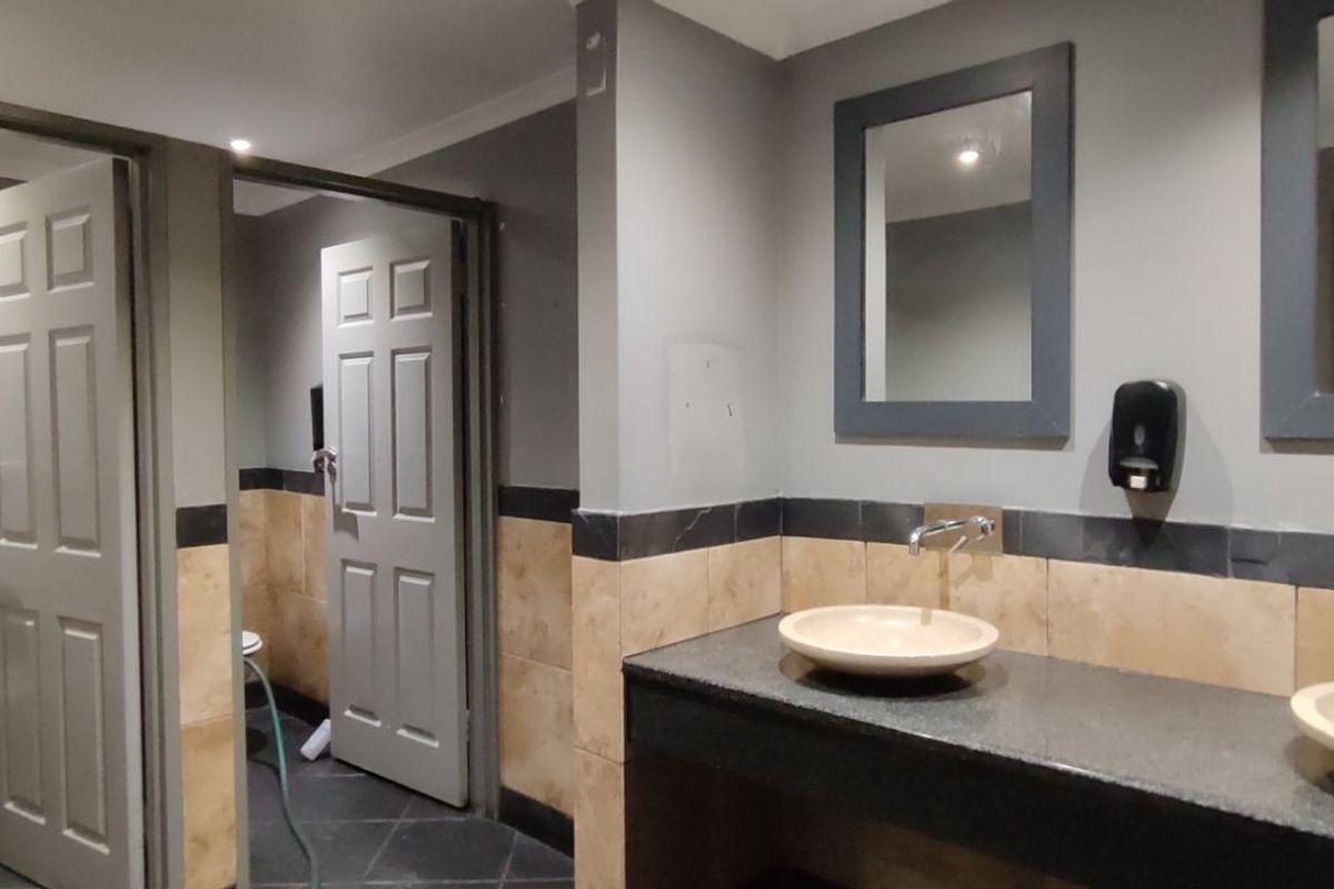 Commercial restroom facility featuring dual vessel sinks with granite countertops, tiled walls, and multiple private toilet cubicles.