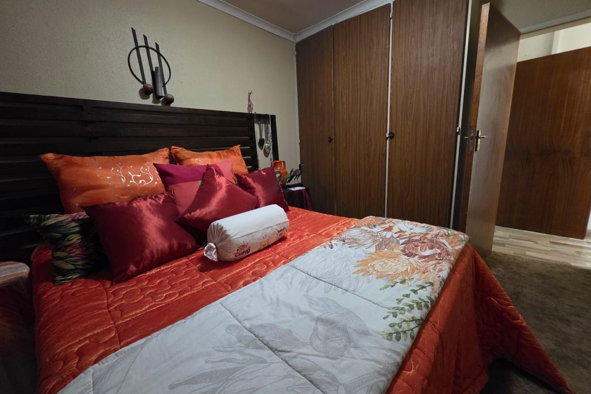 A bedroom featuring built-in wooden cupboards and carpeted flooring.