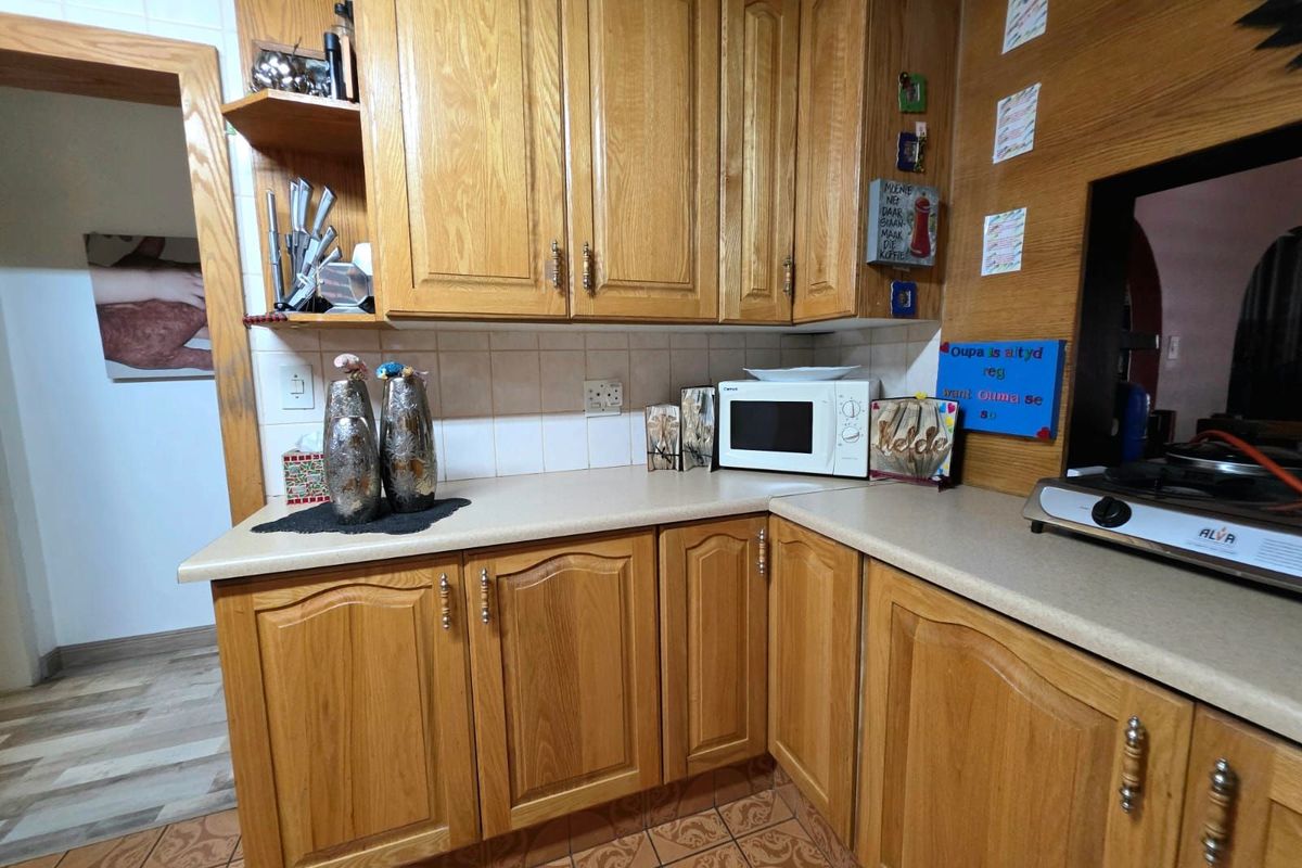 A functional kitchen featuring traditional timber cabinetry, laminate countertops, and tiled flooring, offering a classic layout with ample storage space.