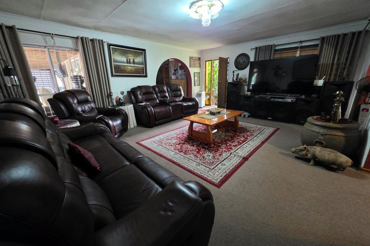 Spacious living room featuring an arched doorway, sliding glass doors leading to a patio, and neutral carpeting.