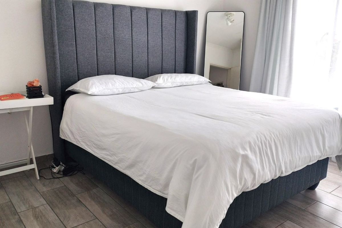 A well-lit bedroom featuring modern wood-look tile flooring and neutral wall finishes, providing a clean and comfortable living space.