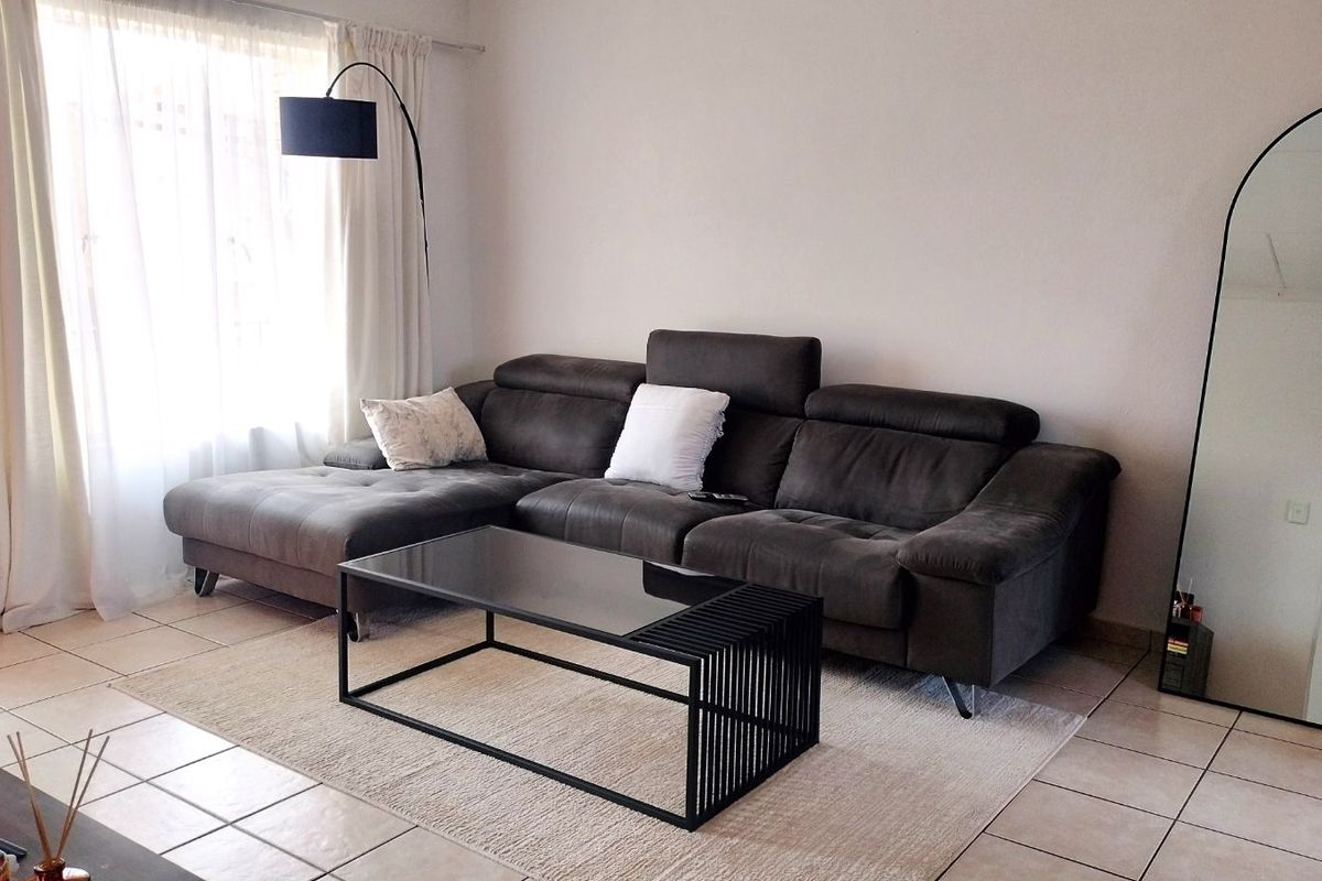 A comfortable living room featuring neutral floor tiles and large windows that allow for ample natural light.
