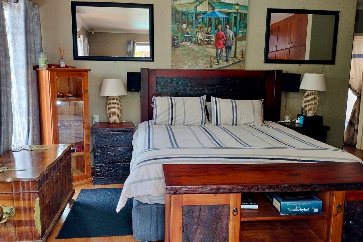A well-maintained bedroom featuring wooden flooring and a prominent built-in headboard design.