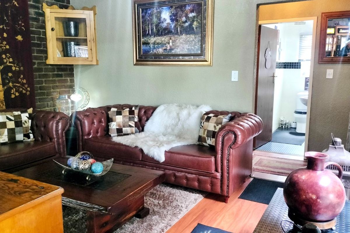 A living room featuring a brick fireplace surround and laminate flooring, with an adjacent doorway leading to a bathroom.
