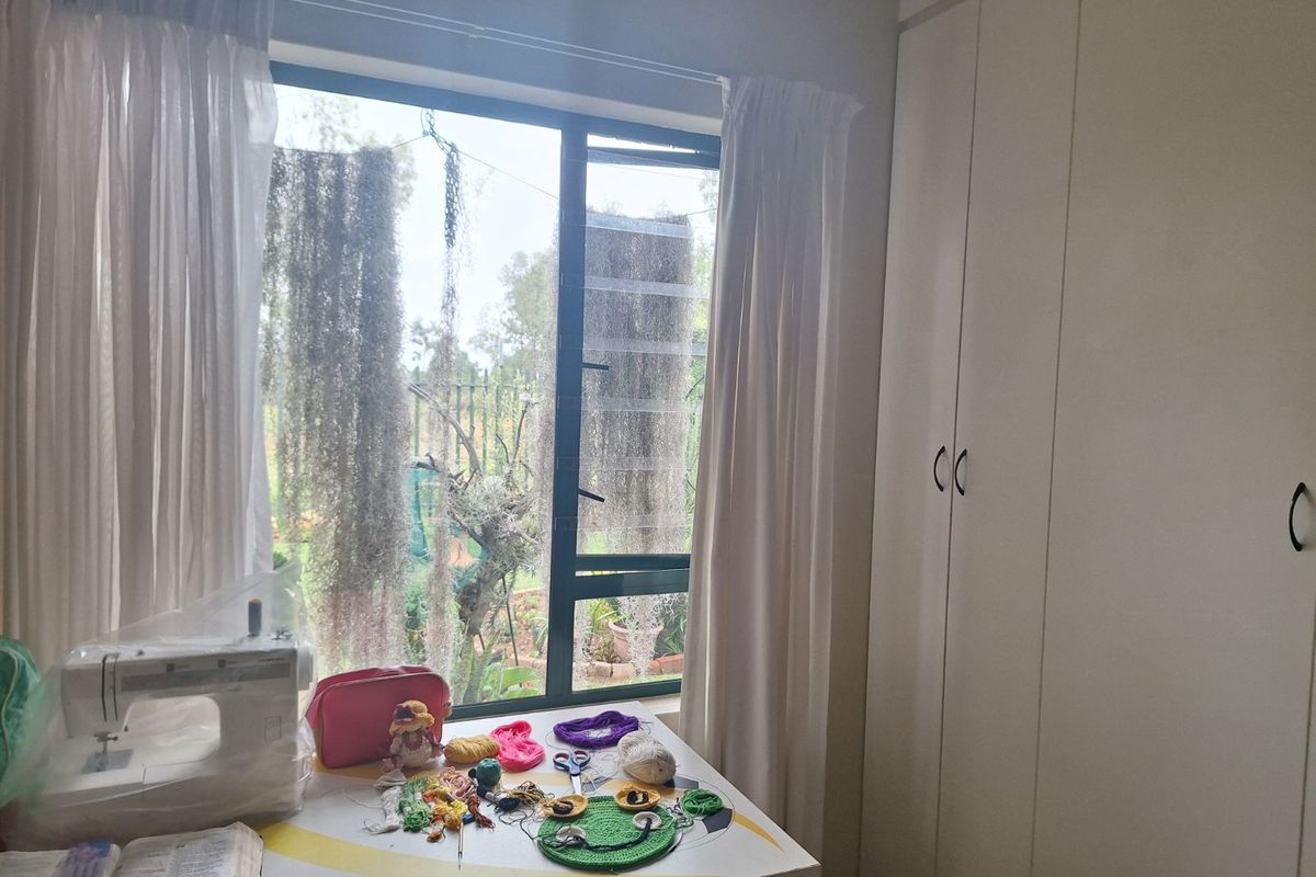 A bedroom featuring built-in cupboards and a large window providing natural light and garden views.