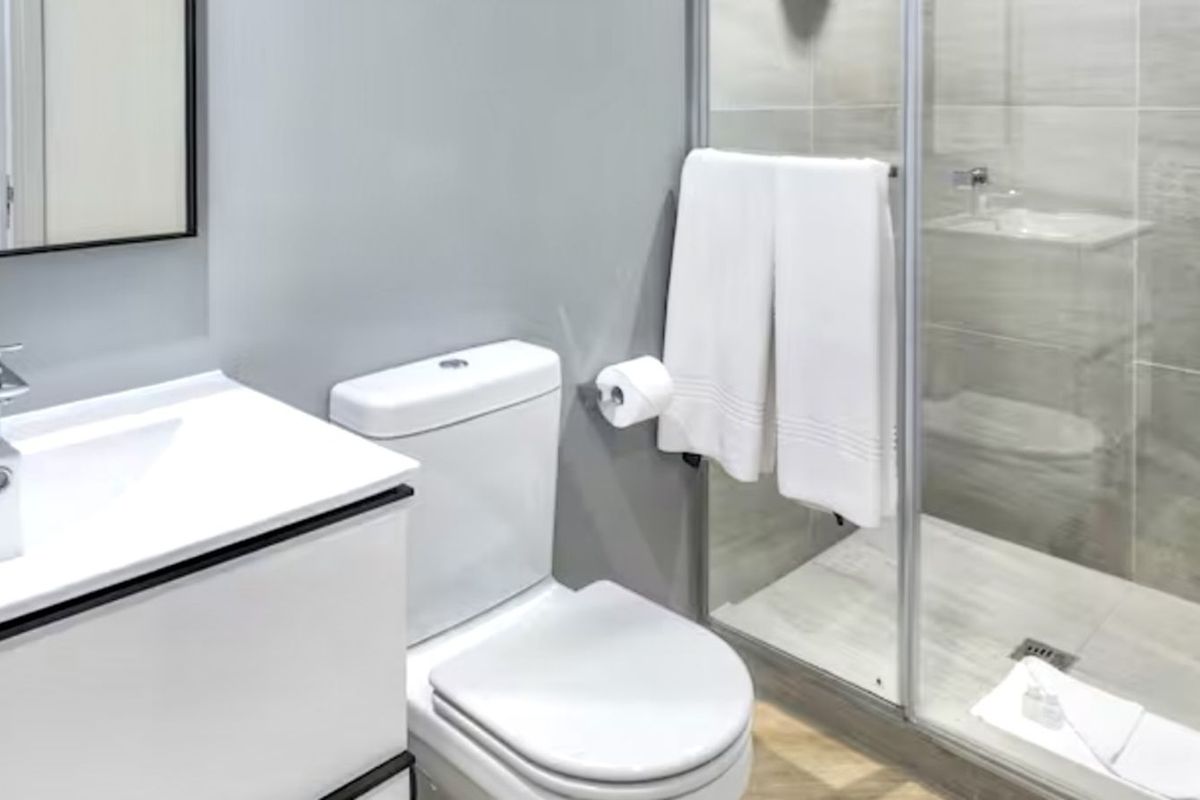 Modern bathroom featuring a glass-enclosed shower, contemporary vanity with basin, and a white toilet with neutral wall tiling.