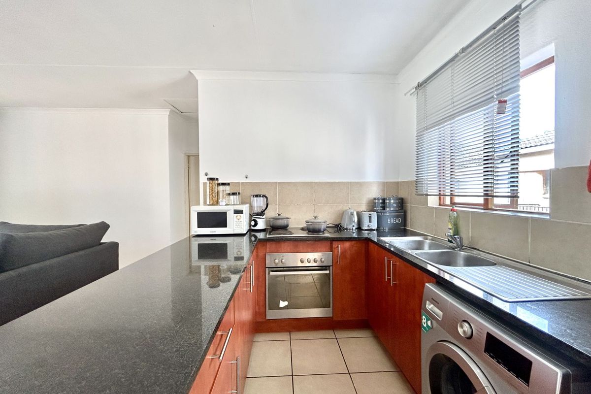 A functional kitchen featuring dark granite countertops, wood-finish cabinetry, a built-in oven, and a double-basin stainless steel sink with integrated laundry plumbing.
