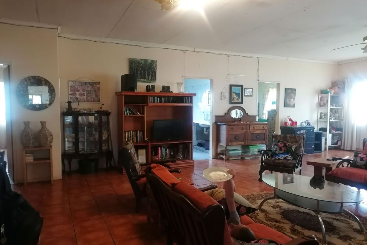 Spacious living area featuring terracotta floor tiles and exposed surface-mounted electrical conduits, offering a functional layout with access to adjacent rooms.