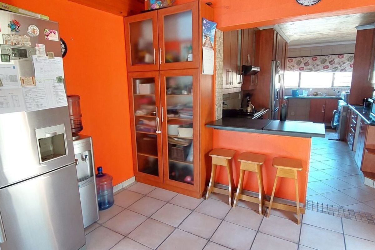A functional kitchen featuring wooden cabinetry, tiled flooring, and a breakfast bar counter, providing a practical layout for daily meal preparation.