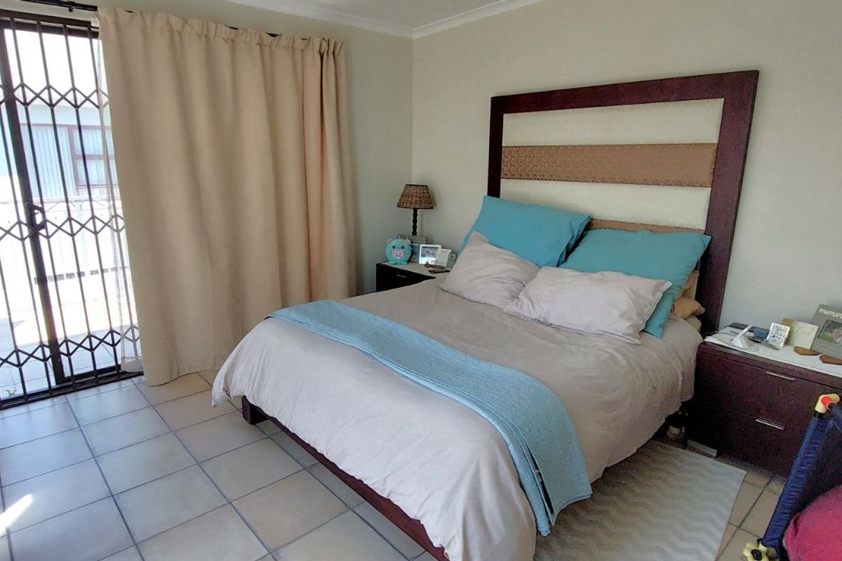 A bedroom featuring tiled flooring and a sliding glass door with a security gate leading to an outdoor area.