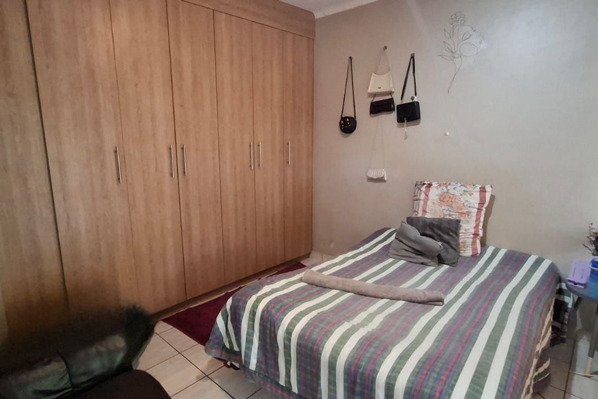A bedroom featuring built-in wooden cupboards and tiled flooring.