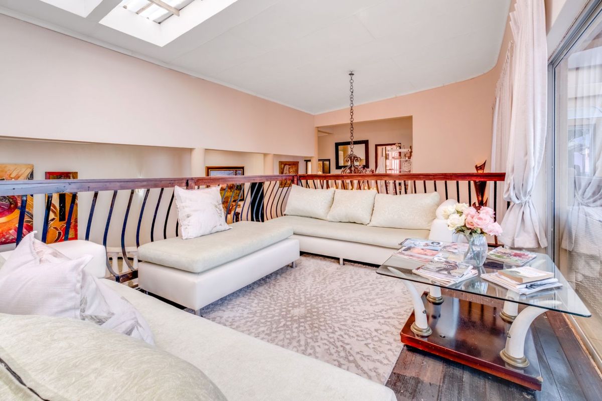 A mezzanine living area featuring a skylight, timber balustrade, and dark wood flooring, overlooking the lower level of the home.
