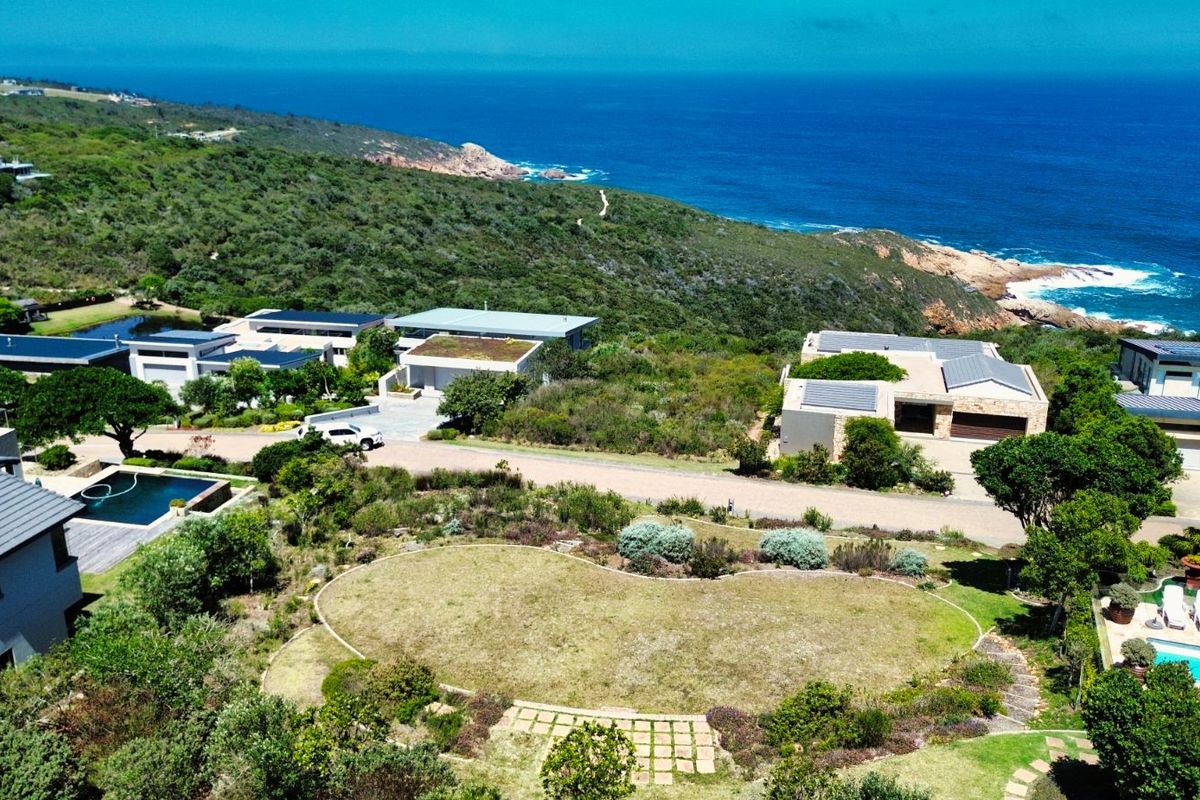 Aerial view of a residential vacant land plot situated in a coastal estate, featuring established landscaping and proximity to the ocean.