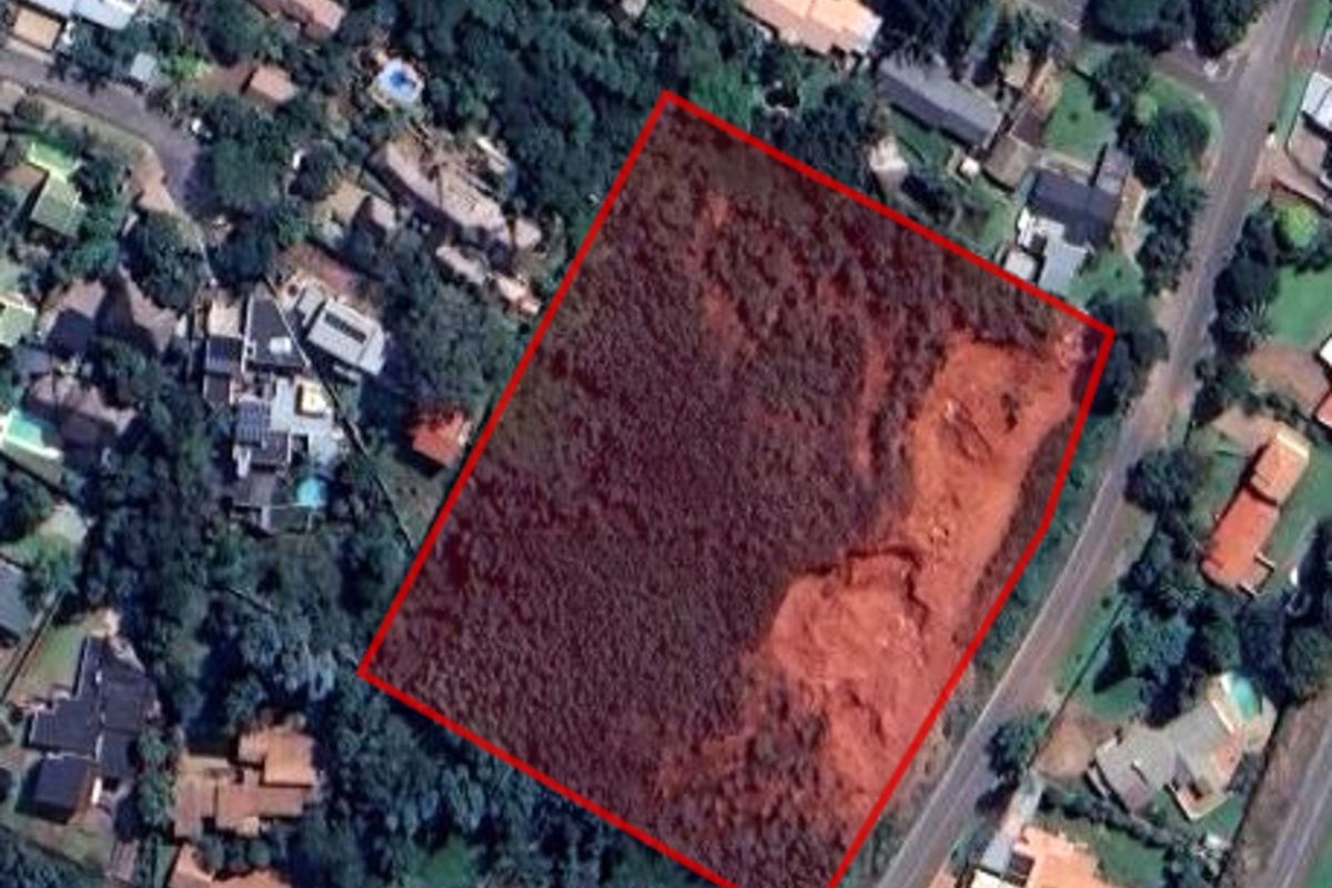 Aerial view of a vacant residential plot outlined in red, situated within an established suburban neighborhood.