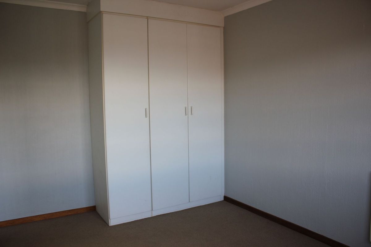 A bedroom featuring built-in white cabinetry and neutral wall finishes with carpeted flooring.