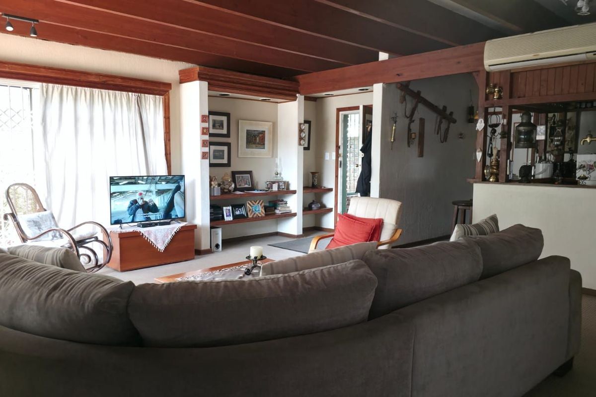 Spacious living area featuring exposed timber ceiling beams, built-in shelving alcoves, and a wall-mounted air conditioning unit.