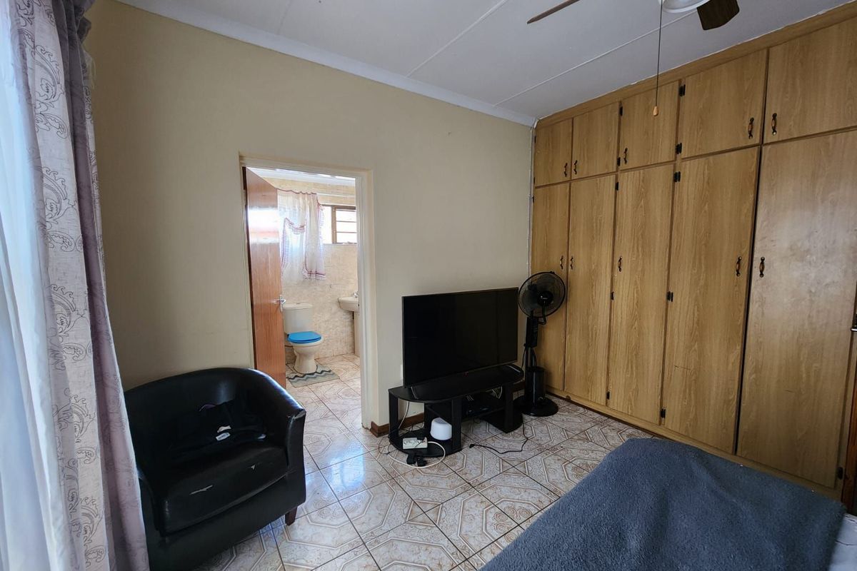 Bedroom featuring built-in wooden cupboards, tiled flooring, and an en-suite bathroom access.