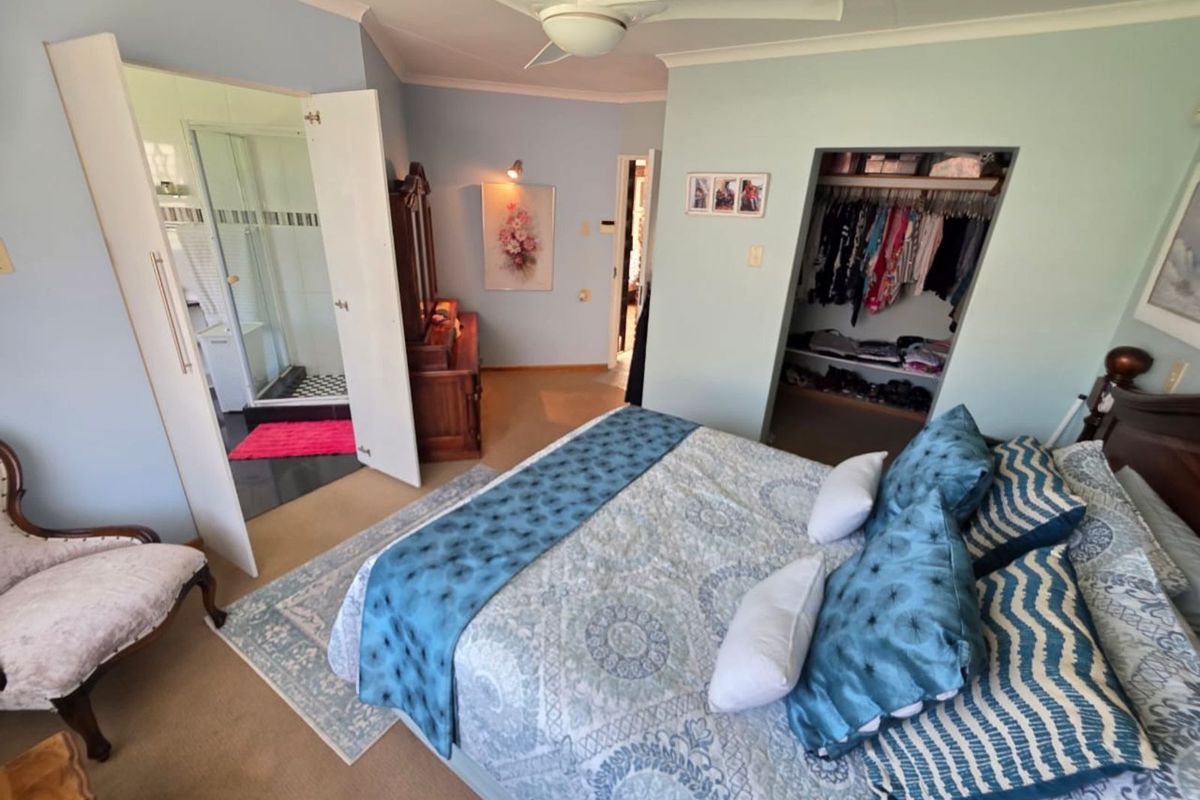 A bedroom featuring a ceiling fan, built-in closet space, and an en-suite bathroom with a shower.