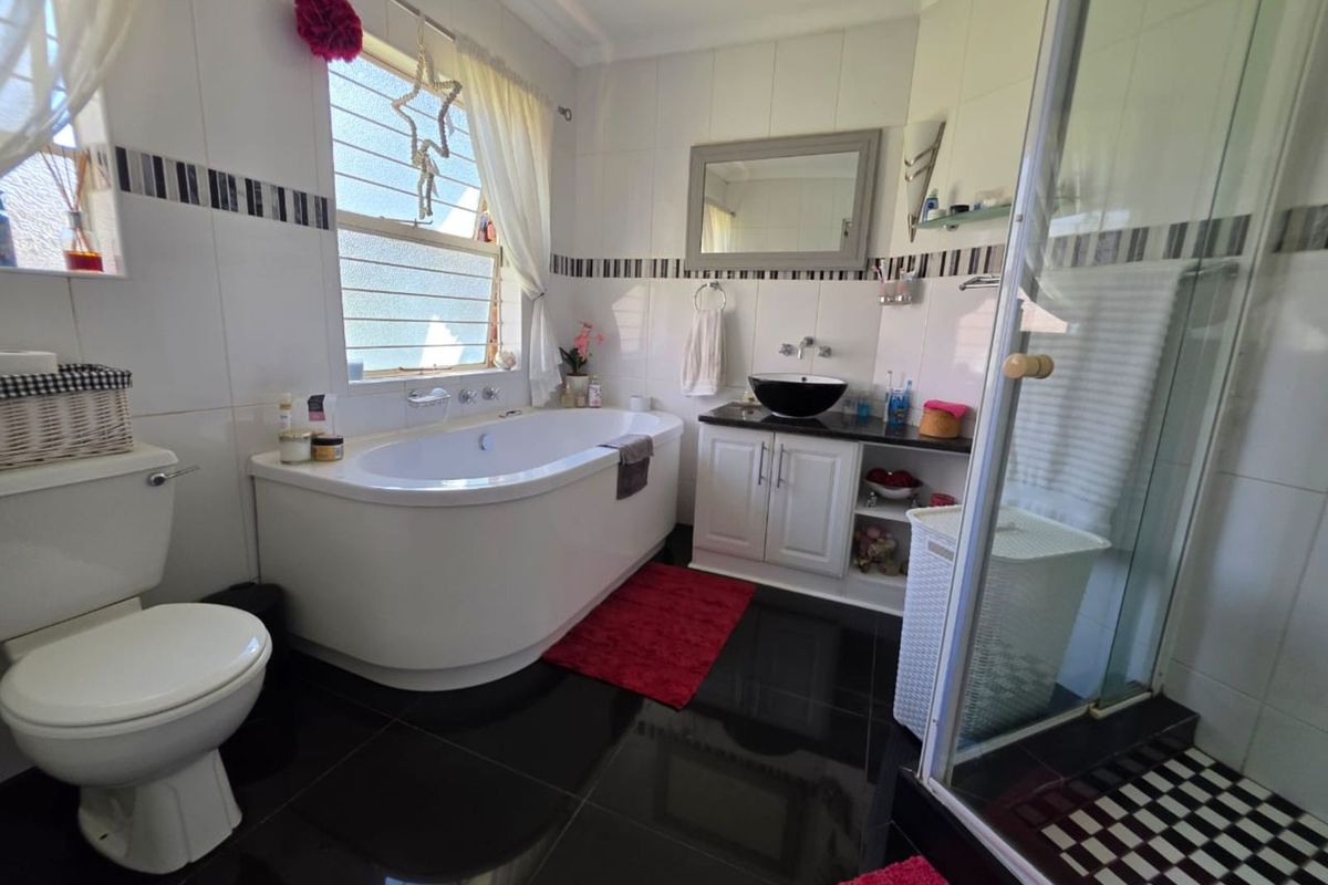 A functional bathroom featuring a corner bathtub, a vanity with a vessel sink, a separate glass-enclosed shower, and tiled flooring.