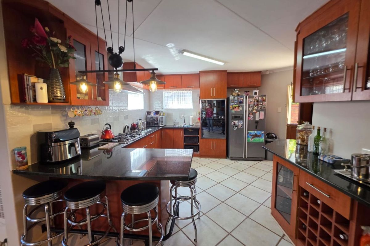 A functional kitchen featuring wooden cabinetry, dark granite countertops, a breakfast bar, and tiled flooring.