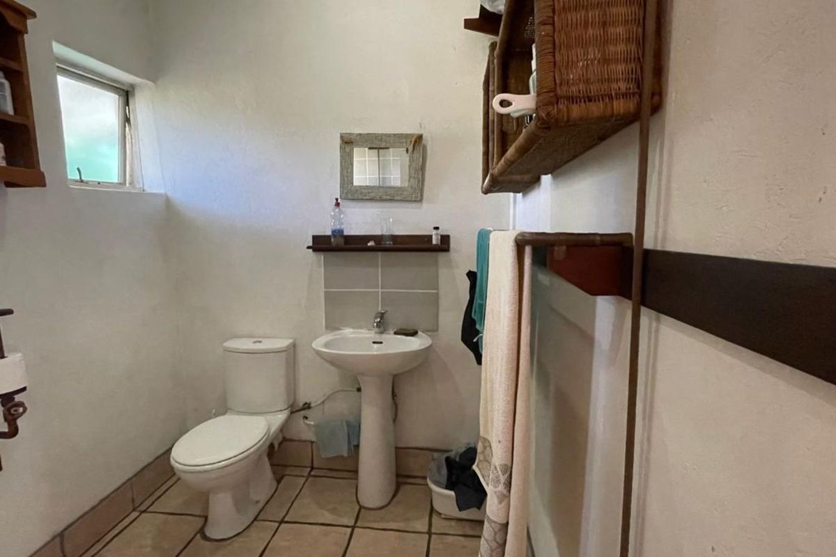 A functional bathroom featuring a pedestal sink, a standard toilet, and tiled flooring, providing essential amenities in a compact layout.