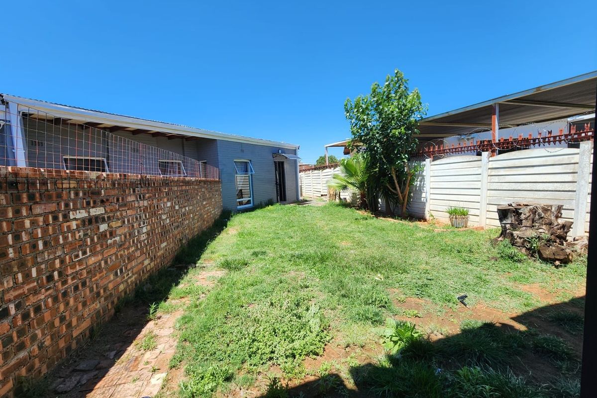 A rear garden area featuring a lawn, brick boundary wall, and precast concrete fencing, providing a private outdoor space at the back of the property.