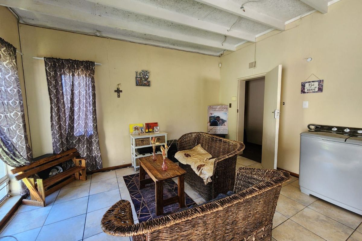 A living area featuring tiled flooring and exposed ceiling beams, currently utilized as a multi-purpose space with laundry facilities.