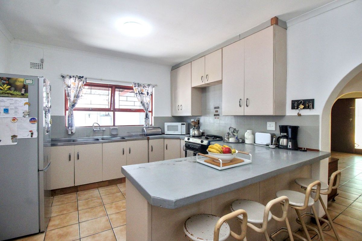 Functional kitchen featuring a breakfast bar, ample cabinetry, tiled flooring, and a double sink with a window view.