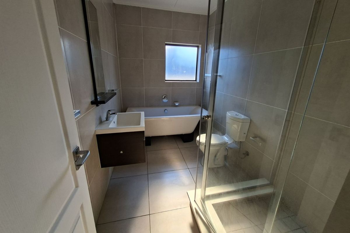 Modern bathroom featuring a glass-enclosed shower, a freestanding bathtub, a wall-mounted vanity, and neutral floor-to-ceiling tiling.