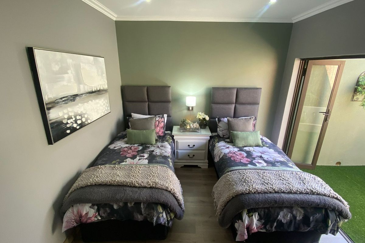 A well-maintained bedroom featuring modern laminate flooring, recessed ceiling lighting, and a glass door providing direct access to an outdoor area.