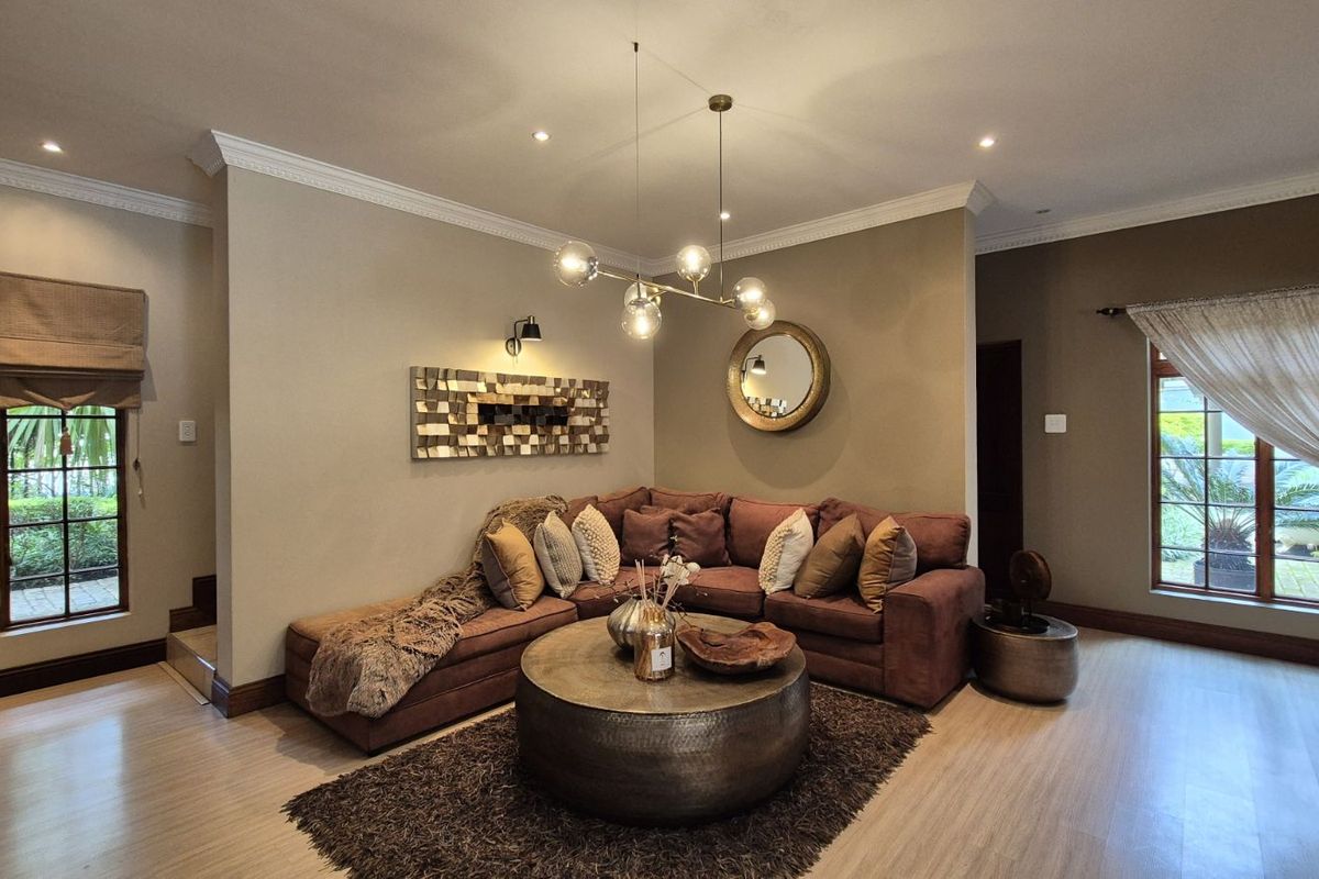 A well-maintained living room featuring recessed downlighting, crown molding, and large windows that provide ample natural light.