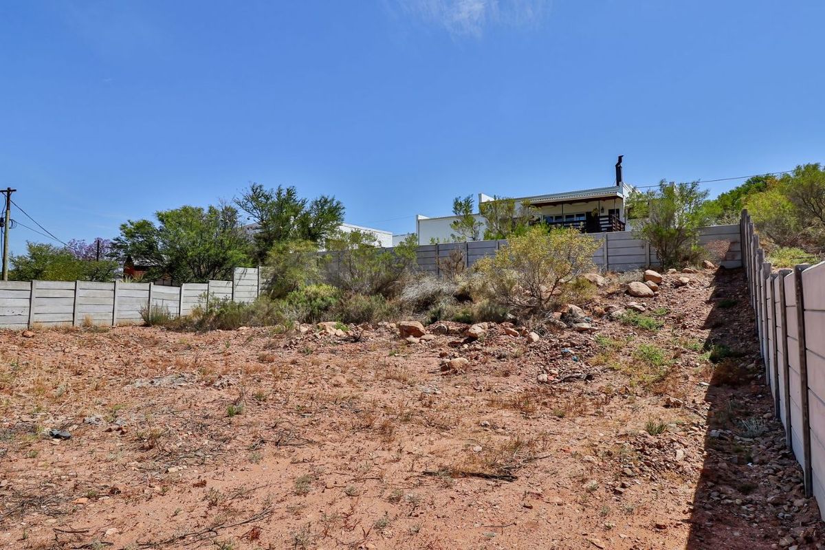 A vacant residential plot featuring natural terrain, enclosed by precast concrete boundary walls, offering a blank canvas for future development.
