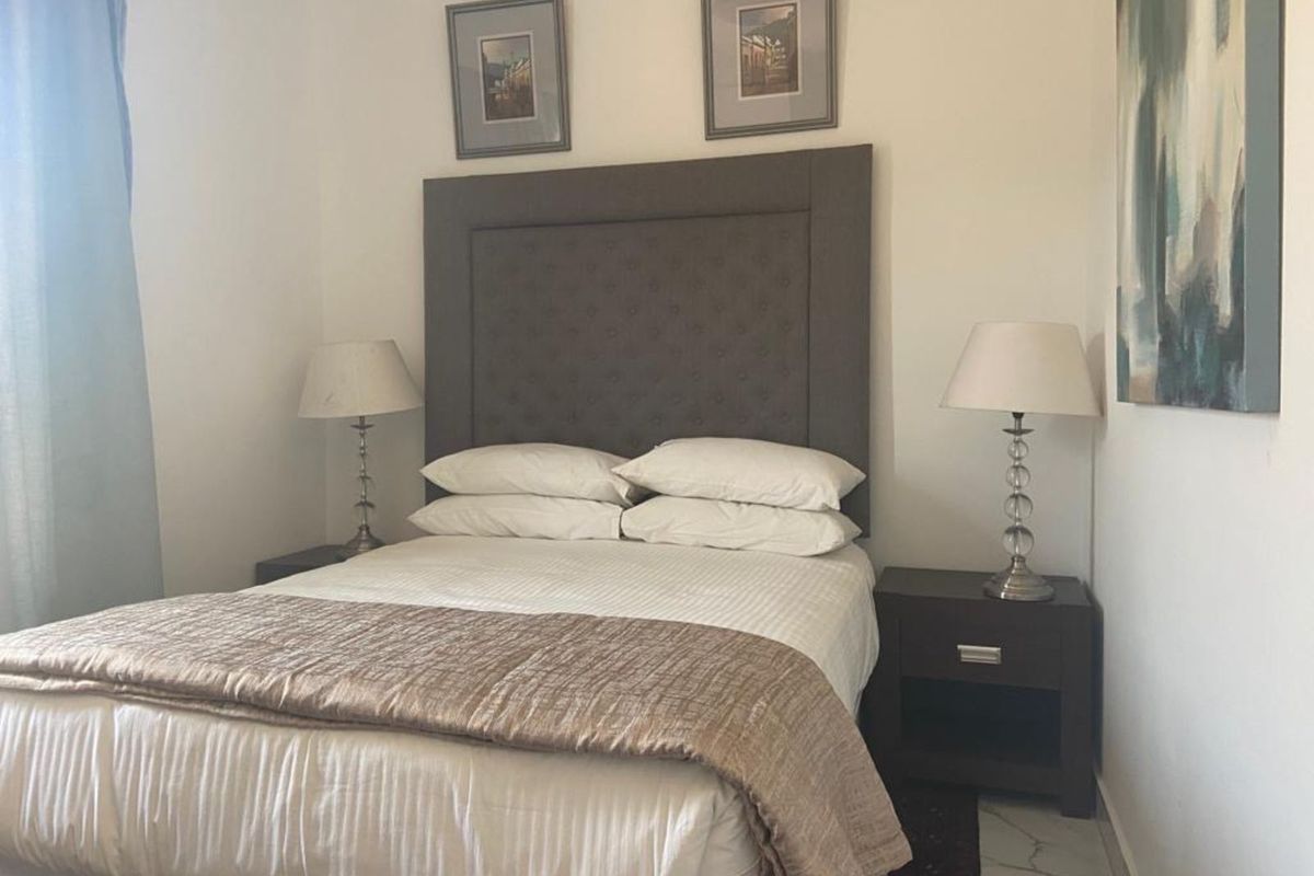 A well-lit bedroom featuring neutral walls and tiled flooring, providing a comfortable and functional sleeping space.