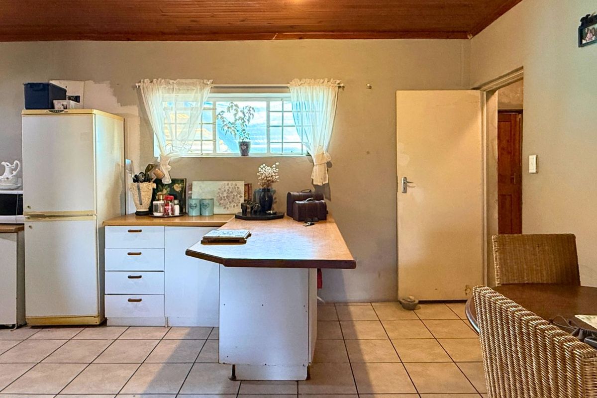A functional kitchen area featuring tiled flooring, wooden ceiling paneling, and a central breakfast counter with built-in cabinetry.