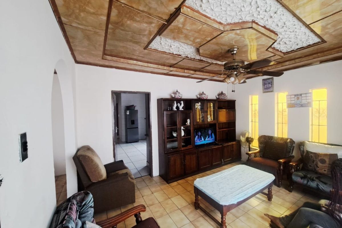 A living room featuring a unique decorative ceiling, tiled flooring, and an arched doorway leading to an adjacent utility space.