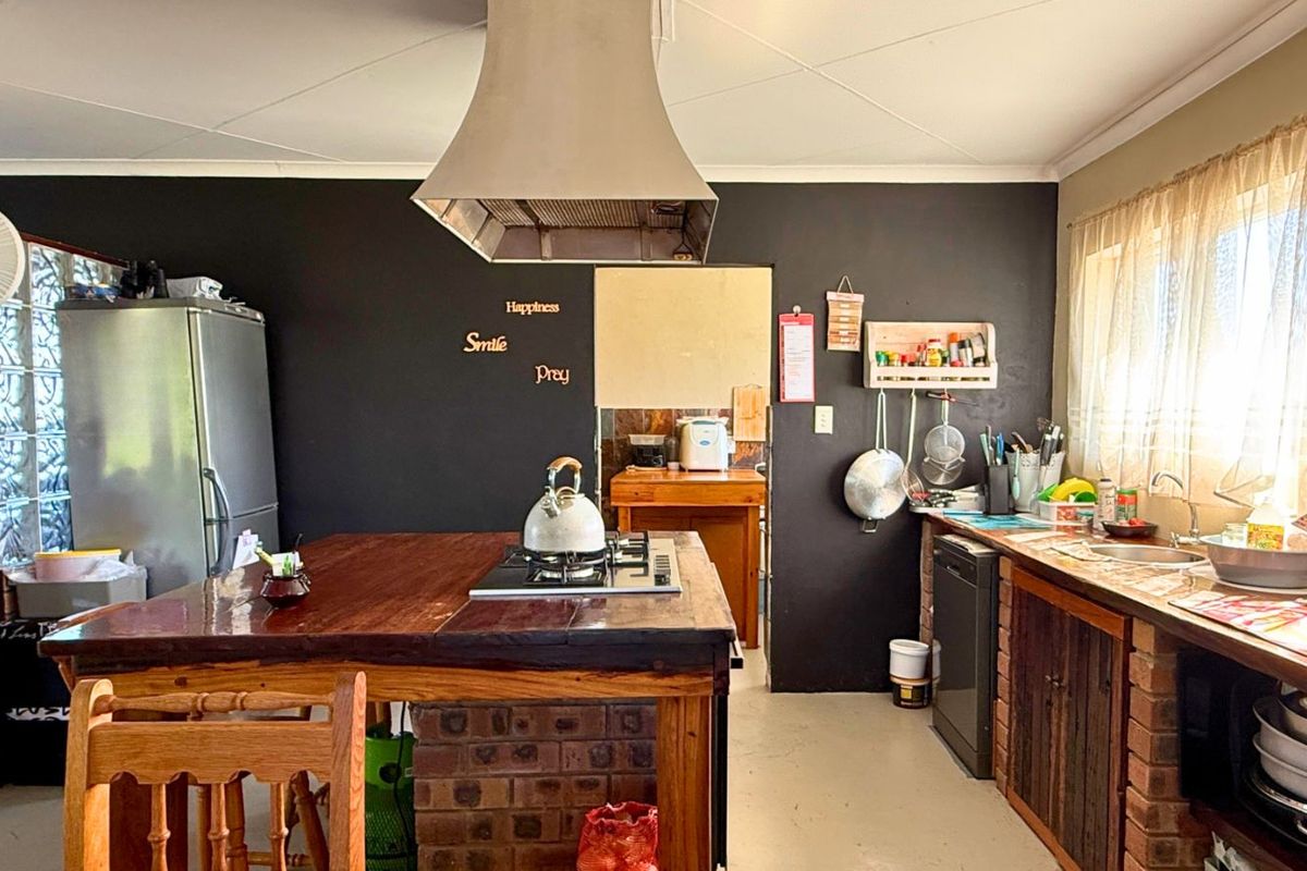A rustic kitchen featuring a central brick-based island with a built-in cooktop, stainless steel extractor hood, and integrated cabinetry with brick accents.