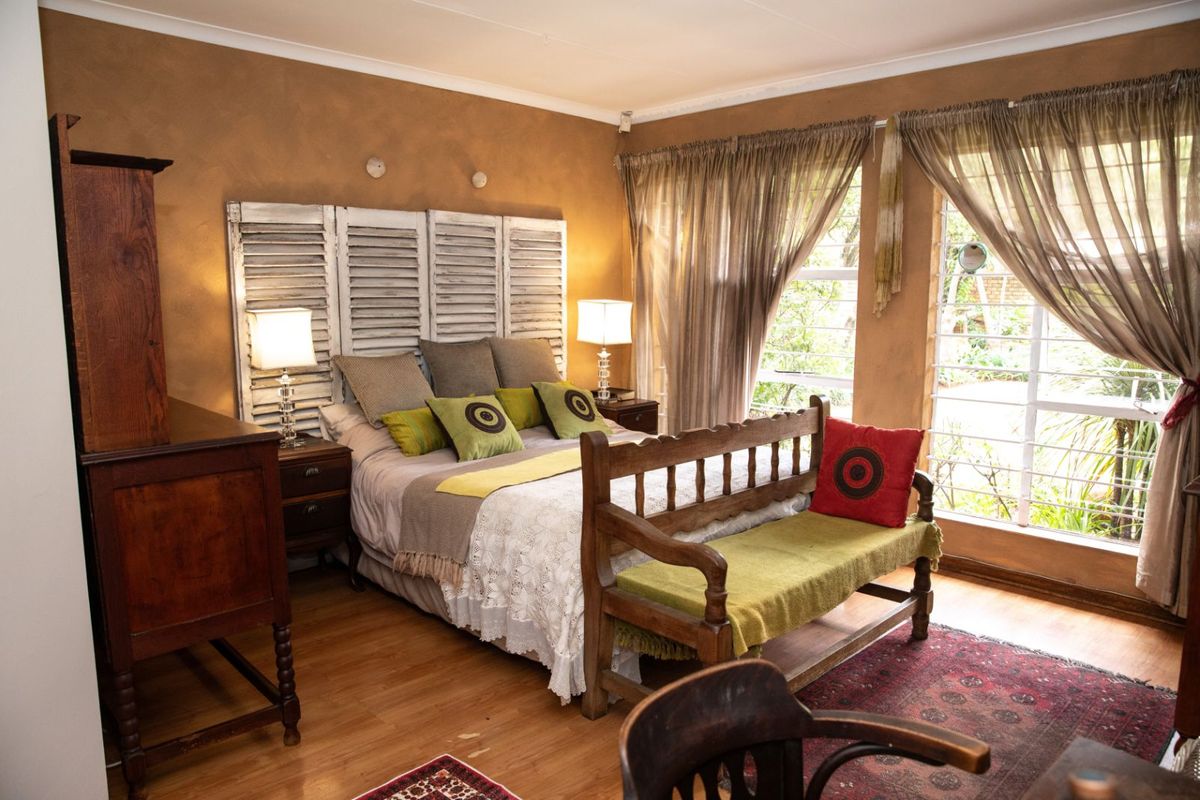 A cozy bedroom featuring warm-toned walls, large windows with natural light, and durable laminate flooring.