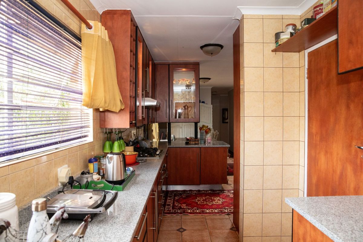 A functional kitchen featuring wooden cabinetry, granite-style countertops, and tiled wall finishes, providing a practical workspace with integrated storage solutions.
