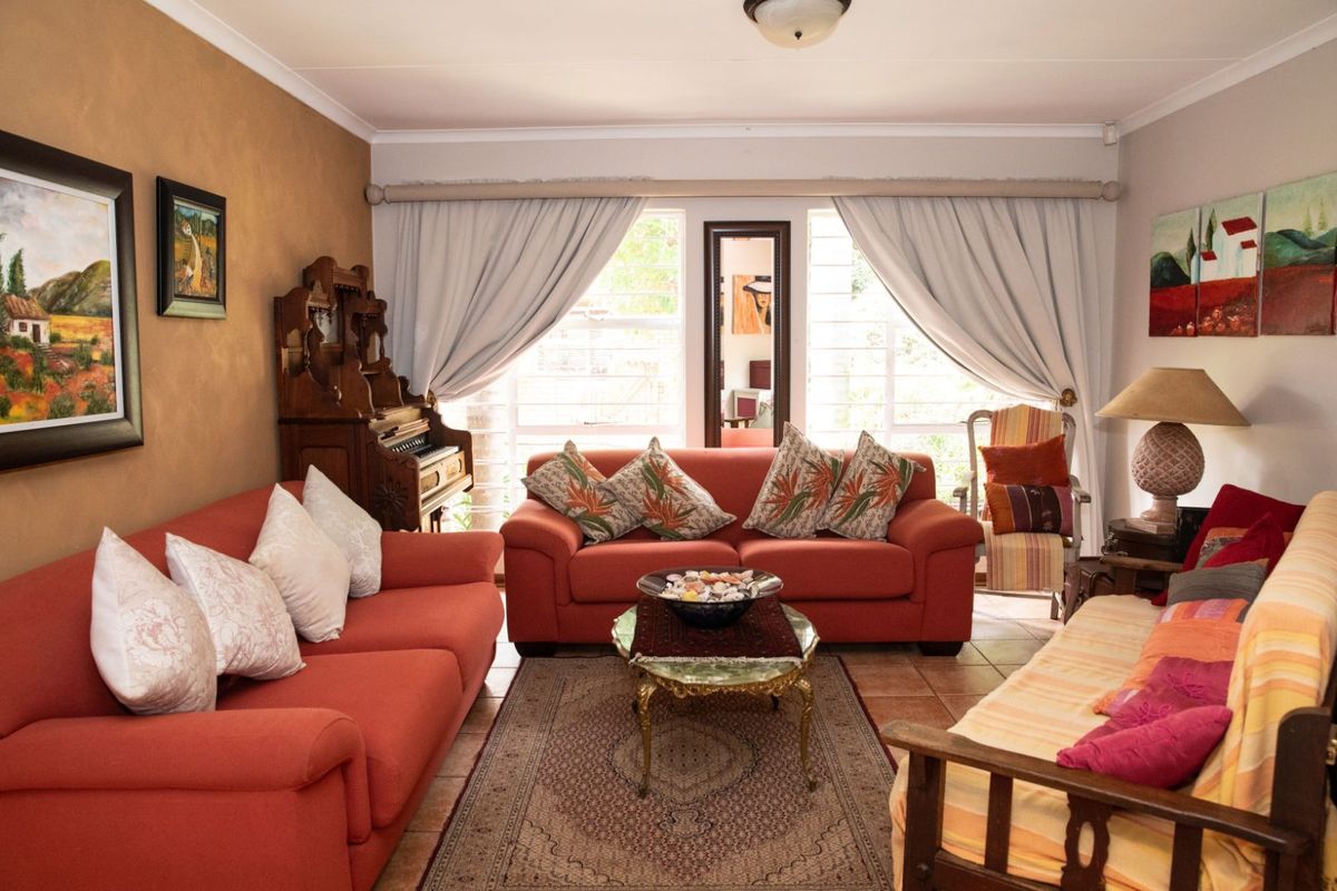 A comfortable living room featuring tiled flooring, large windows with curtain treatments, and neutral wall finishes.