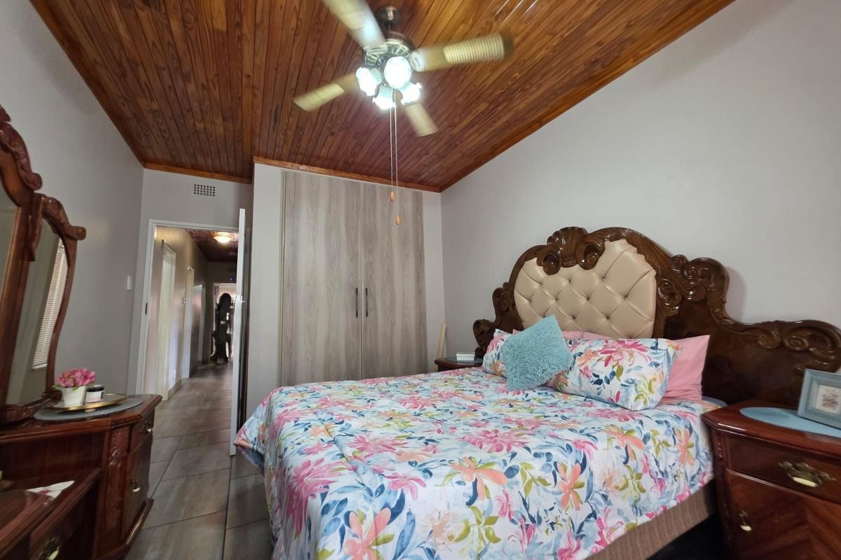 A bedroom featuring a wooden tongue-and-groove ceiling, built-in cupboards, and tiled flooring, providing a functional and comfortable living space.