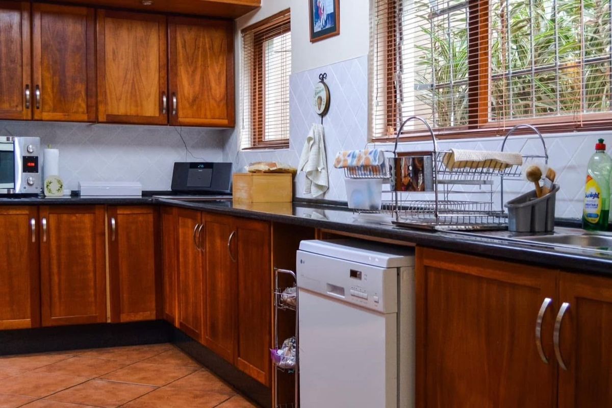 A functional kitchen featuring warm-toned wooden cabinetry, dark granite countertops, tiled backsplash, and integrated space for a dishwasher.